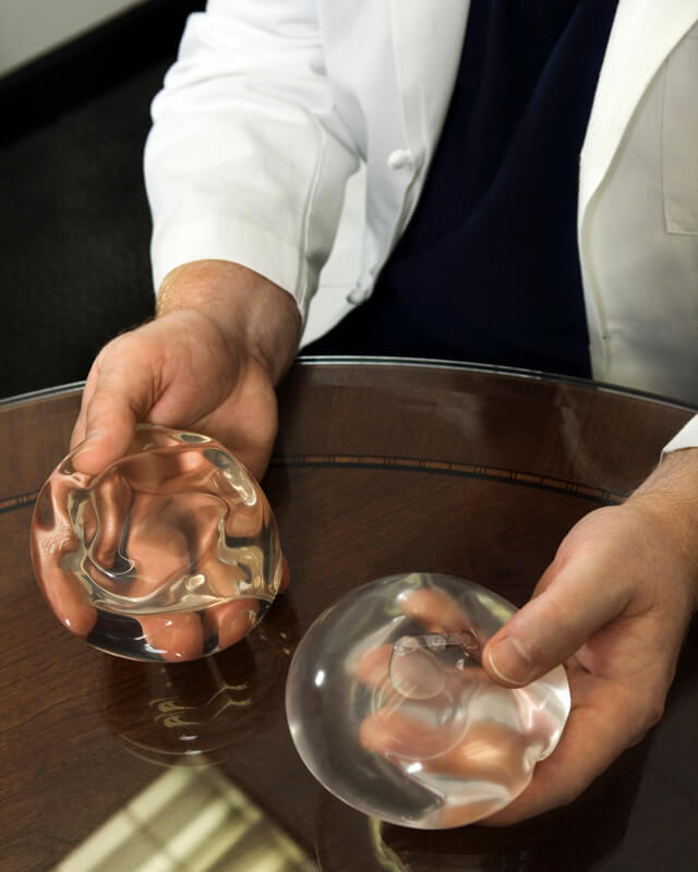 Doctor showing different breast implants